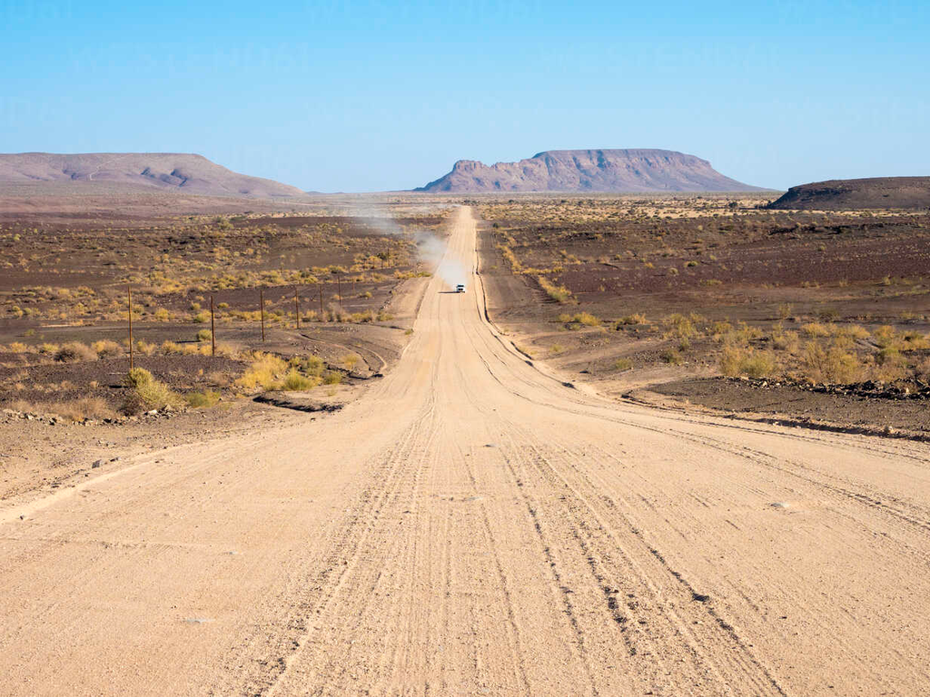 Een eindeloze zandweg door het indrukwekkende landschap van Namibië